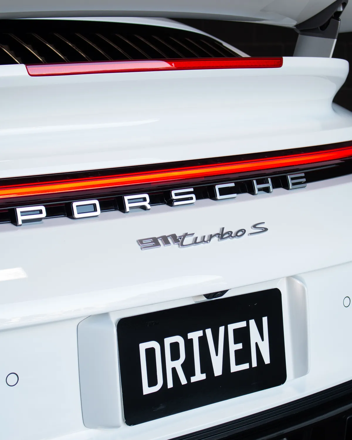 Porsche 911 Turbo S badge close-up with DRIVEN plate